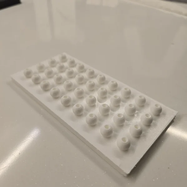 A 3D printed bead array plate with multiple small beads on a rectangular base from Print3D.pk.