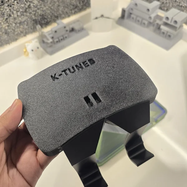 Textured black K-Tuned 3D printed automotive part held in hand by Print3D.pk.