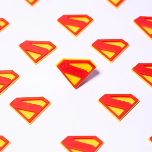 3D printed Superman logos in red and yellow, available at Print3D.pk for unique collectibles.
