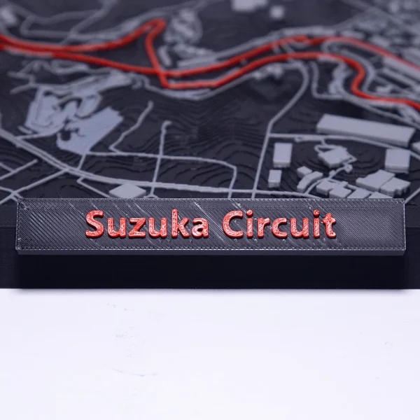 A detailed 3D printed Suzuka Circuit model with red track and grey buildings from Print3D.pk.