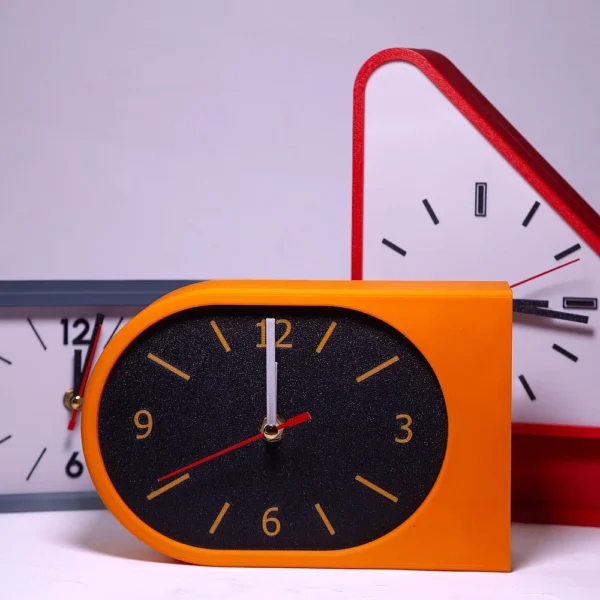 Custom 3D printed retro alarm clocks in orange, grey, and red by Print3D.pk.